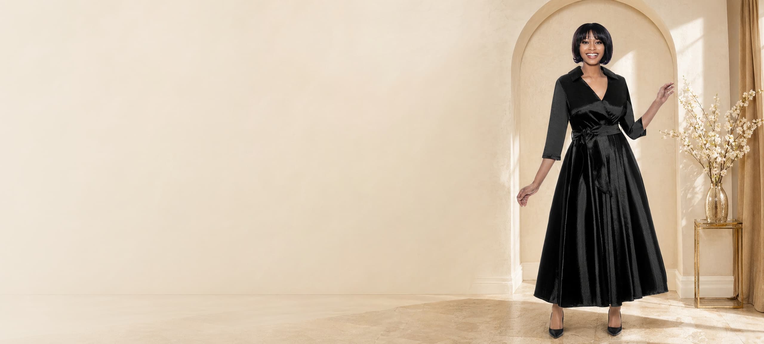 An elegant woman in a refined black gown, photographed in a New Orleans courtyard